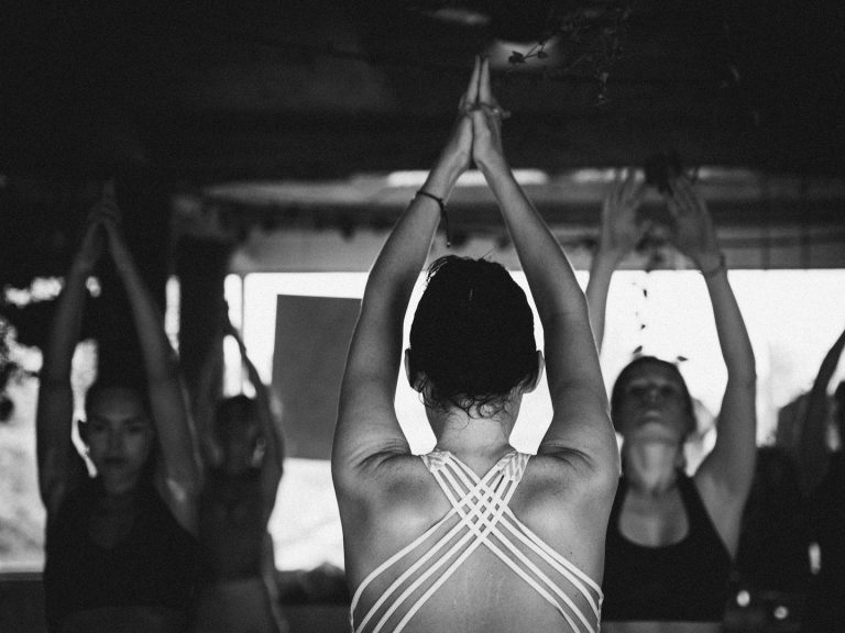 Sonnengruß Raubling Gruppe von Frauen in Yoga-Pose, Hände über dem Kopf, fokussierte Atmosphäre.